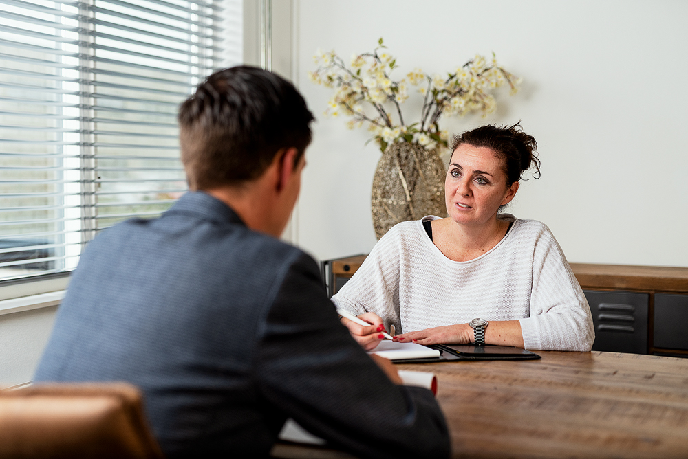 Twee mensen in gesprek aan een kantoor tafel